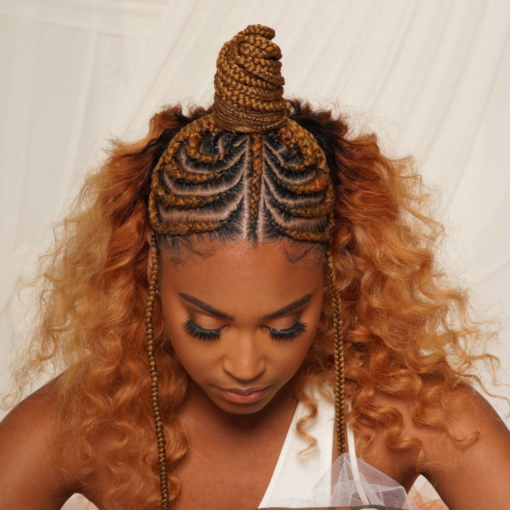 Photo of the top of a woman's head as she looks down. She has a half-updo with braids in a topknot.