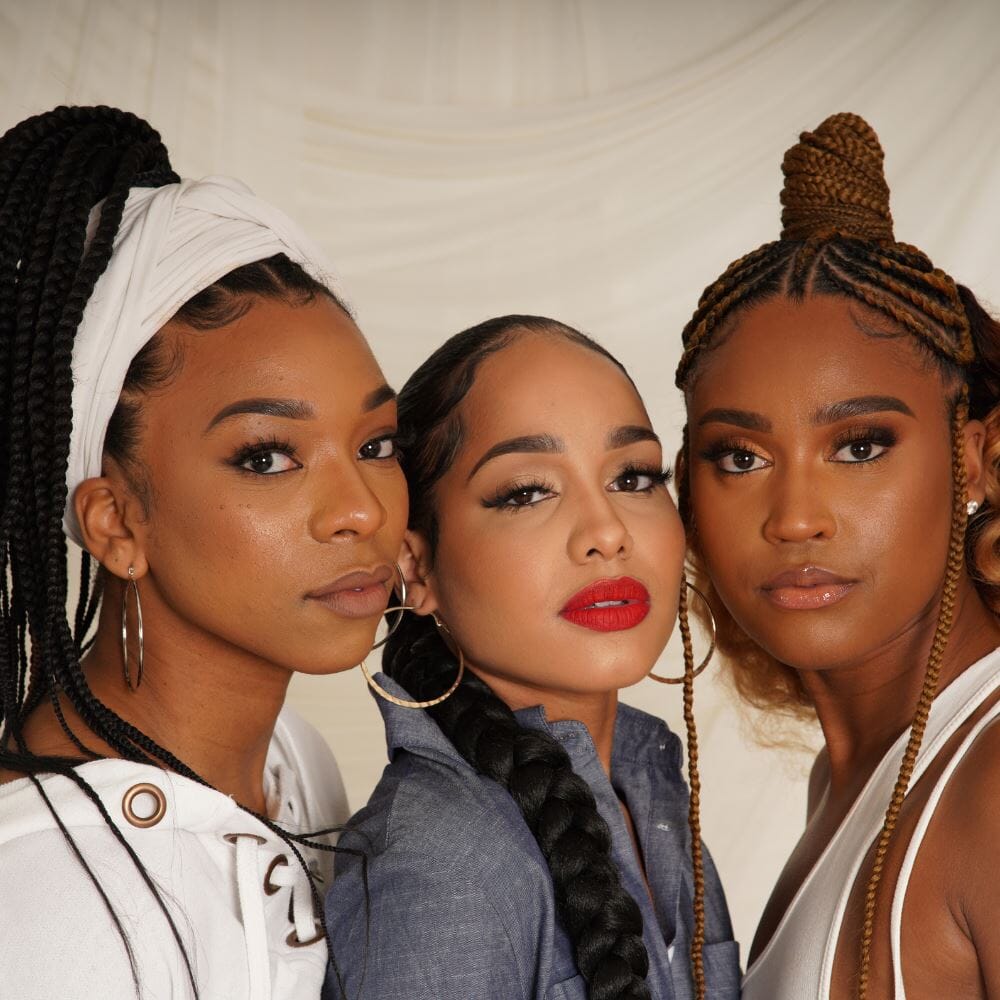 Close-up of a group of three women with various braided hairstyles, like a braided ponytail and box braids.