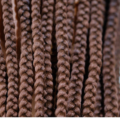 A close-up of many strands of narrow dark brown braids.