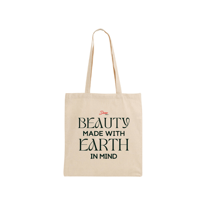 Overhead shot of a flat white canvas totebag with black text that reads "Beauty Made With Earth in Mind."